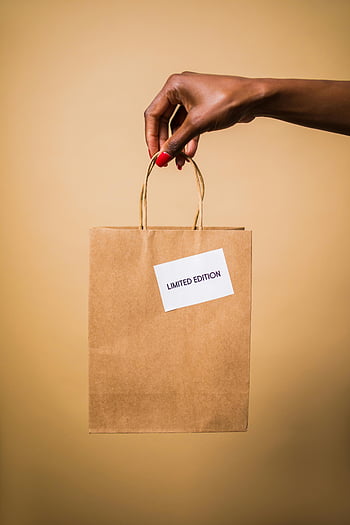 woman hand, paper bag, limited edition, brown paper bag, shopping bag, orange background, close-up, hand holding, limited edition bag, red nails, brown background