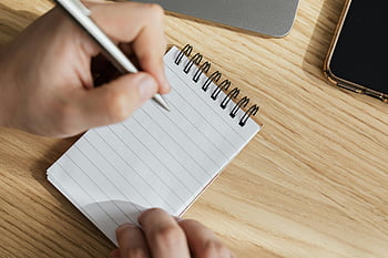 crop man, pen, opened notebook, spiral notebook, wooden desk, focused work, writing, adult, desk workspace, notepad, hands writing