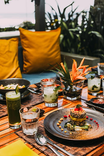 outdoor dining, colorful dishes, tropical cocktails, exotic dining, vibrant food, restaurant table, dining setup, tropical drinks, outdoor restaurant, vibrant cocktails, exotic food