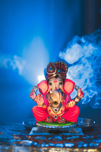 Socha Ganapati, růžová barva, socha ganesha, podsvícený kouř, duchovní prostředí, Nanded India, Tradiční Ganesha, náboženské umění, hinduistické božstvo, slavnostní dekorace, kulturní ikona