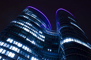 Hochhaus, Nachtzeit, moderner Wolkenkratzer, leuchtende Lichter, lila Akzente, Nachthimmel, Flachwinkelansicht, Stadtarchitektur, Stadtbild, beleuchtetes Gebäude, zeitgemäßes Design