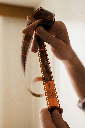 hands holding film, photographic film, close-up hands, film strip, selective focus, detailed close-up, gentle handling, film photography, analog photography, vintage film, film development