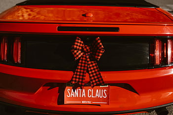 Christmas decorations, luxurious car, red car, Santa Claus-themed license plate, holiday bow decoration, festive car, car decorations, Santa Claus license plate, holiday car, Christmas car, red bow