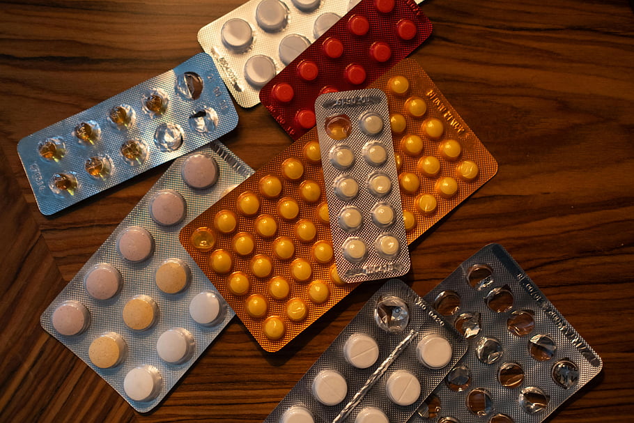 medicine pills, colorful pills, blister packs, wooden surface, top view, various pills, medication packages, tablet blister, medical pills, table view, prescription pills