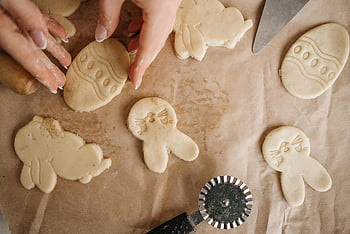 Easter-themed cookies, bunny shapes, baking paper, hands preparing, white dough, wax paper, Easter cookies, cookie cutter, baking preparation, festive baking, Easter baking