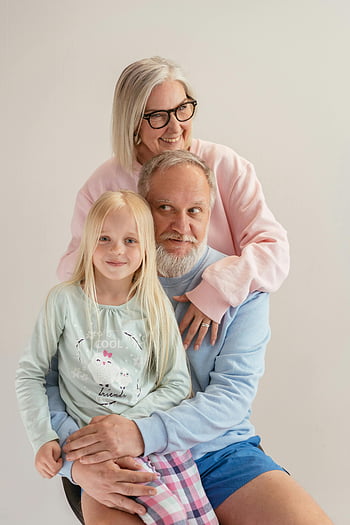 elderly couple, granddaughter, family portrait, indoor photo, smiling together, grandmother, grandfather, multi-generation family, happy family, casual clothing, emotional moment