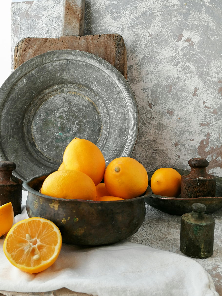 oranžové plody, kulatá šedá betonová mísa, Vintage zátiší, čerstvé citrony, rustikální prostředí, měděná mísa, plátky pomeranče, rustikální dekor, vinobraní výzdoba, ovocná boule, fotografie zátiší