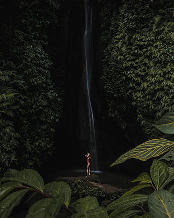 woman in red swimsuit, waterfall, tropical foliage, nature, posing, majestic waterfall, lush vegetation, tranquility, outdoor scene, natural beauty, travel photography