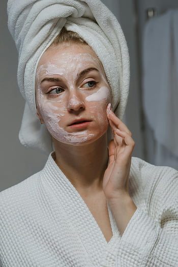 Gesichtscreme, Hautpflege-Routine, Frau auftragen Creme, Bademantel, Handtuch auf dem Kopf, Gesichtsbehandlung, Hautpflege, Schönheitsroutine, Selbstversorgung, Gesichtsmaske, Hautpflegeprodukte