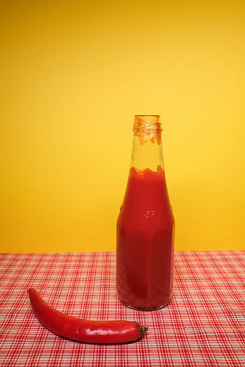ketchup bottle, red chili pepper, red sauce, glass bottle, red checkered cloth, yellow background, table, condiment, spicy food, food photography, red pepper