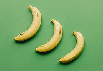 modne bananer, grønn overflate, overhead view, levende grønn bakgrunn, tre bananer, moden frukt, gule bananer, grønn bakteppe, fruktfotografering, matfotografering, minimalistisk sammensetning