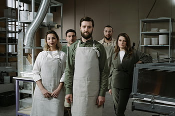 колеги с престилки, цех, индустриална работилница, съвместна дейност, професионалисти в престилки, група професионалисти, стои в работилницата, престилки, промишлена среда, работна среда, работа в екип в работилница