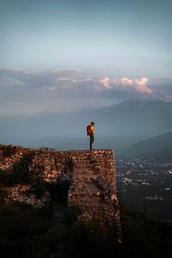 man standing on rocky cliff, lone traveler, stone cliff, mountainous landscape, vast view, outdoor adventure, scenic overlook, nature photography, travel photography, hiking, backpacker