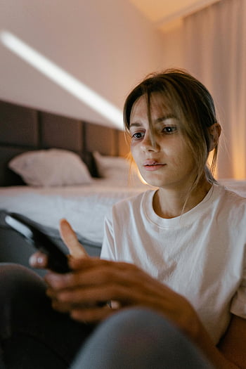 femeie, cămașă albă, ținând telefonul mobil, expresie îngrijorată, dormitor, Setare interioară, smartphone, îmbrăcăminte lejeră, poză relaxată, Mediul de origine, spatiu personal