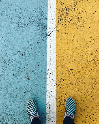 black-and-white checkered shoes, slip-on shoes, vibrant yellow asphalt, blue painted asphalt, bold contrast, checkered pattern, close-up shoes, colorful pavement, street style, fashion footwear, urban footwear