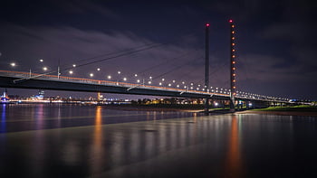 visutý most, noční fotografie, osvětlený most, klidná řeka, světla města, odraz na vodě, městské krajiny, noční scénu, architektonická fotografie, dlouhé expozice, panoráma města
