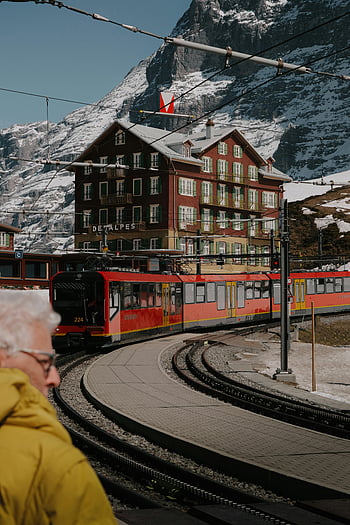 Swiss Alps, Jungfrau region, Interlaken, red train, mountain hotel, winter landscape, snow-covered mountains, Swiss flag, European travel, alpine architecture, railway station