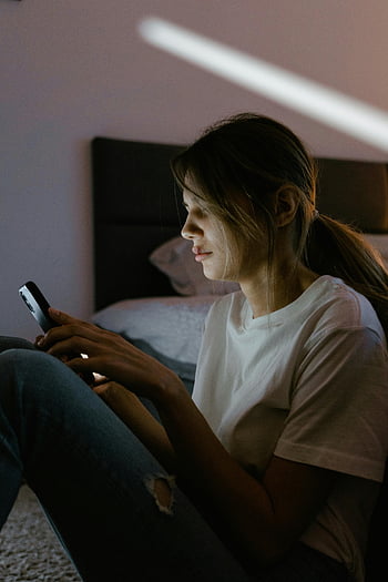 스마트 폰을 사용하는 여성, 아늑한 침실, 캐주얼 의류, 측면보기, 하얀 셔츠를 입은 여자, 스마트 폰 사용, 실내 설정, 편안한 분위기, 캐주얼 라이프 스타일, 개인 기술, 가정 환경