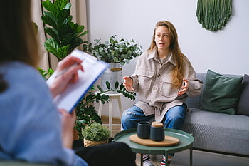 therapy session, woman discussing issues, counselor, modern office, indoor plants, therapy room, mental health, professional consultation, woman in therapy, therapist taking notes, comfortable setting