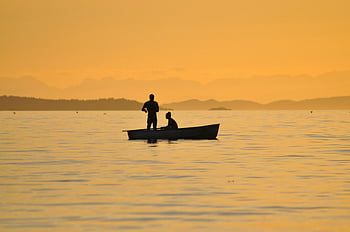 fishing, calm lake, sunset, silhouetted, golden sky, two people, boat, body of water, peaceful scene, outdoor activity, nature photography