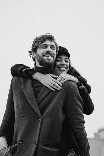 woman hugging man, black coat, black and white photograph, joyful couple, embracing, warmth, affection, couple hug, black coat man, black and white couple, affectionate couple