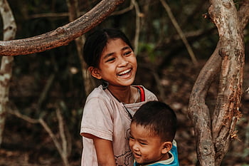 Girl Smiling, Happy siblings, laughing together, playing outside, among trees, outdoor fun, childhood joy, natural setting, brother and sister, playful moment, forest play
