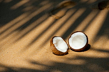 opened coconut, coconut halves, sandy beach, sunlit sand, palm fronds, beach shadows, tropical beach, coconut on sand, coconut shell, beach coconut, coconut water
