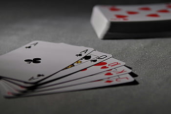 playing cards, poker hand, dimly lit, detailed view, winning hand, card deck, ace of clubs, royal flush, card game, gambling, casino