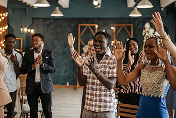 group of people, standing, praising, joyful, diverse, adults, clapping, singing, lively, indoor setting, celebration