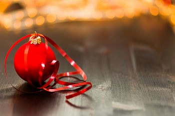 rote Weihnachtskugel, rotes Band, Holzoberfläche, Nahaufnahmen, Festliche Bauer, Dekoratives Band, Holztisch, verschwommene Lichter, Feiertagsdekoration, Weihnachtsdekoration, Nahaufnahme Bild