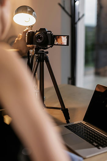 osoba držící fotoaparát, dslr fotoaparát, Nastavení stativu, vnitřní vlogging, osvětlení lampy, nahrávání videa, Tvorba obsahu, fotografické vybavení, digitální fotoaparát, nastavení vloggeru, notebook poblíž