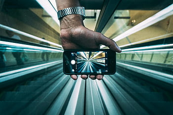 Űrszürke iPhone 6, mozgólépcső nézet, okostelefon -lencse, dinamikus perspektíva, kreatív lövés, kezében telefon, modern technológia, városi fotózás, mozgólépcsőfotózás, iphone fotózás, dinamikus kompozíció