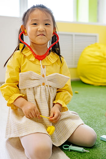 jeune fille, robe jaune, jouer au docteur, stéthoscope, jeux d'intérieur, jouer un rôle, jeu d'enfants, médecin ludique, activité à l'intérieur, jeu d'enfant, stéthoscope jouet