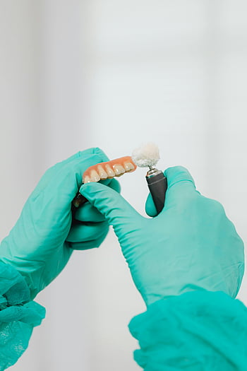 leštění zubní protézy, Péče o zuby, dentální hygiena, detailní záběr, zubař, leštící nástroj, Zubní rukavice, zubní postup, stomatologické vybavení, Údržba protézy, zdraví zubů