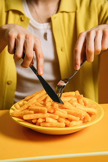 young man, eating fries, crispy snacks, knife and fork, yellow background, plate of fries, enjoying food, casual dining, food photography, meal time, dining experience