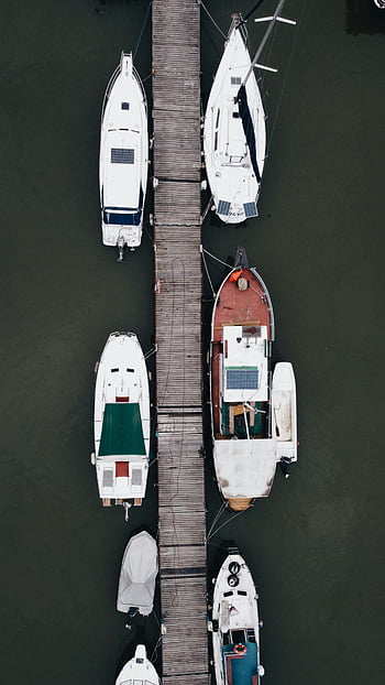 boats moored, wooden pier, sailboats, yachts, top-down aerial shot, peaceful dock, Beograd Serbia, marina, waterfront, nautical scene, docked boats