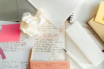 corrections, paragraph, crumpled paper, cluttered workspace, notebooks, pens, creative chaos, writing process, editing, desk, stationery