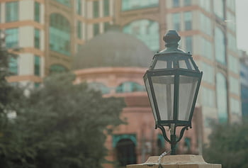 vintage street lamp, black street lantern, classic architecture, blurred city backdrop, turned off lamp, urban scene, outdoor lighting, historical streetlight, cityscape background, architectural details, street furniture