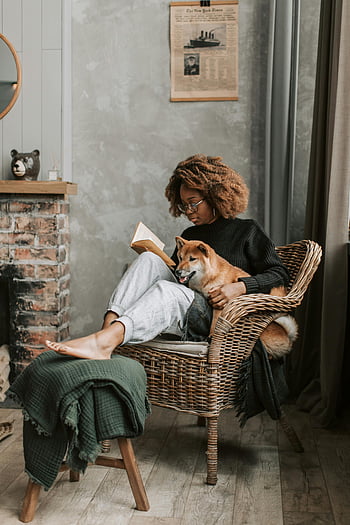 woman reading, Shiba Inu, cozy home, relaxing, book, wicker chair, fireplace, indoor setting, comfortable, pet, lifestyle