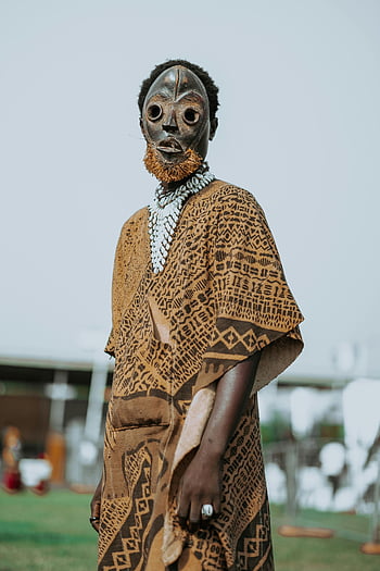 africký muž, Tradiční africký oděv, kmenová maska, venkovní portrét, Černoch, Kulturní oblečení, Etnické šaty, venkovní nastavení, africké kultury, Tradiční maska, kmenové oblečení