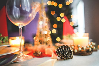 Christmas table setting, candles, pinecones, wine glass, festive decor, holiday atmosphere, warm lighting, acorn, long stem glass, festive table, Christmas decorations