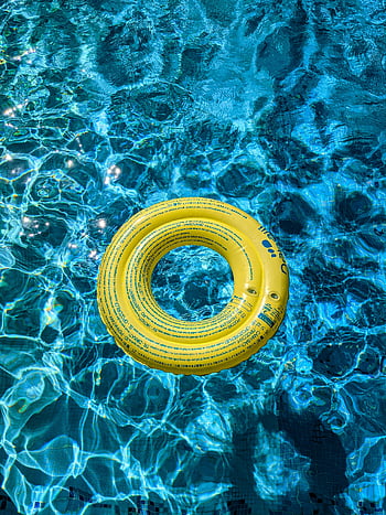 yellow swim ring, swimming pool, clear blue water, sunlit pool, vibrant yellow, floatation device, pool accessory, water safety, outdoor recreation, summer fun, pool float