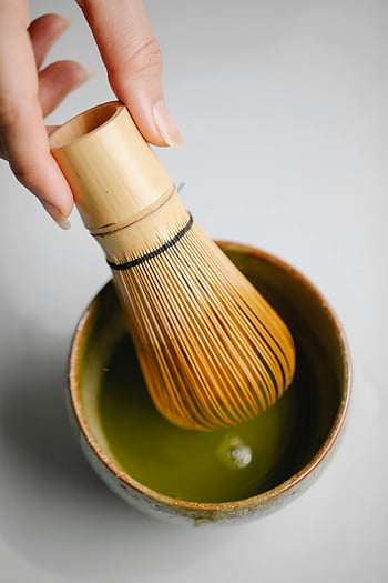 matcha čaj, bambusový šlehač, keramický pohár, Tradiční japonská kultura, detail, Příprava Matcha, čajový ceremoniál, zelený čaj, Ruka drží šlehnutí, Matcha mísa, Šlehačka čaje