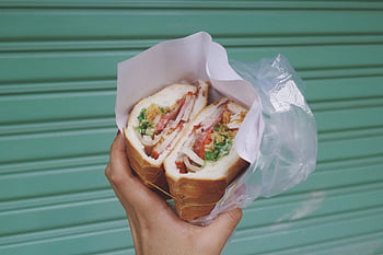 hand holding sandwich, takeaway sandwich, fresh sandwich, Ho Chi Minh City, Vietnam street food, close-up sandwich, sandwich packaging, sandwich for takeaway, Vietnamese sandwich, hand holding food, street food photography