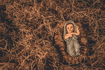Jesus Christ figurine, nativity scene, baby Jesus, surrounded by straw, symbolizing hope, tradition, religious icon, Christmas decoration, manger scene, baby Jesus figurine, nativity display
