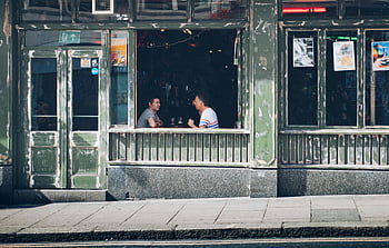 two men, eating, facing each other, inside store, vintage-style café, casual conversation, interior, café, vintage, window view, urban setting