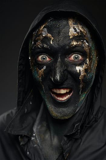 black and gold face mask, Halloween costume, creepy mask, close-up portrait, black face paint, gold accents, spooky makeup, dark background, hooded figure, eerie expression, Halloween makeup