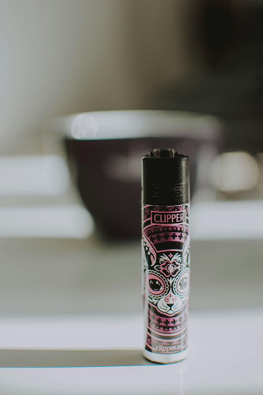 Clipper lighter, cat design, colorful lighter, close-up photo, indoor setting, surface, Clipper brand, decorative lighter, cat-themed lighter, indoor photography, lighter design