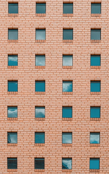 brick building, square windows, symmetrical facade, evenly spaced windows, blue sky reflection, architectural design, urban architecture, modern building, brick wall, window pattern, building exterior