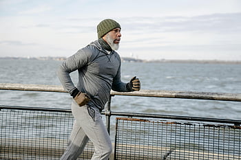 Uomo anziano che fa jogging, stile di vita attivo, mattina d'inverno, Lungomare, Uomo di colore che corre, argine, esercizio all'aperto, vita sana, Fitness per anziani, corsa costiera, Allenamento invernale